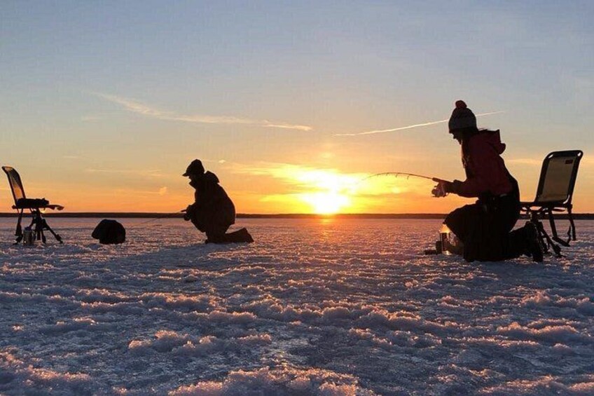 A person fishing on a frozen lake at sunset. 2