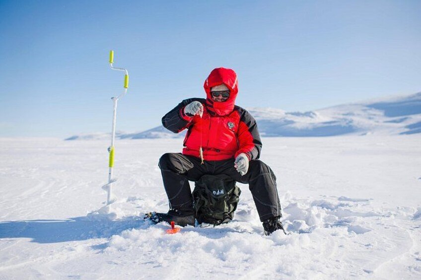 A person in a red jacket sitting on the snow with a flagpole in the background. 5