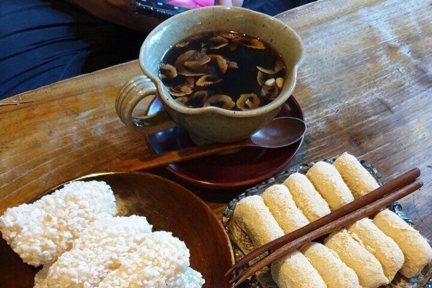 Un tavolo di legno con una tazza di tè, una ciotola di riso e un piatto di mochi. 4