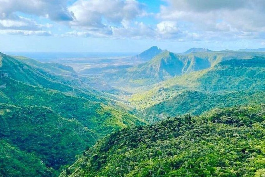A mountainous landscape with dense green vegetation and a valley. 1