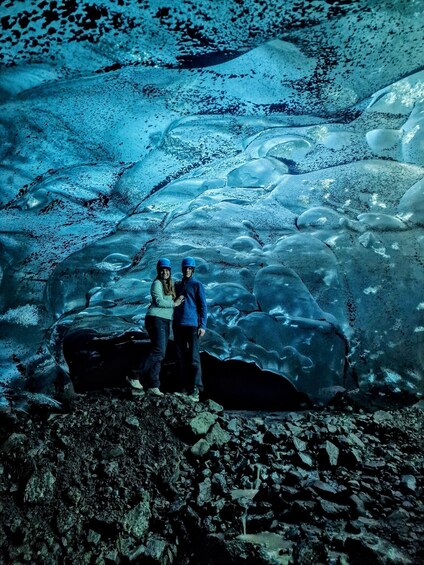 Two people standing on a rocky surface with a glacier in the background. 3