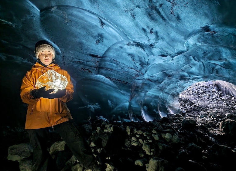 A person holding a large ice block in a glacier cave. 1
