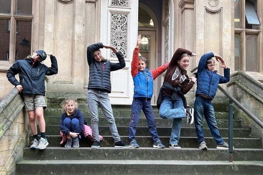 Children on steps, some wearing jackets, with a building in the background. 3