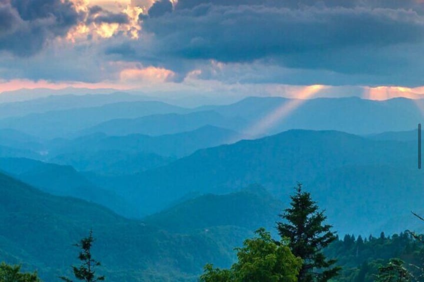 A mountainous landscape with a clear sky and sunlight filtering through clouds. 1