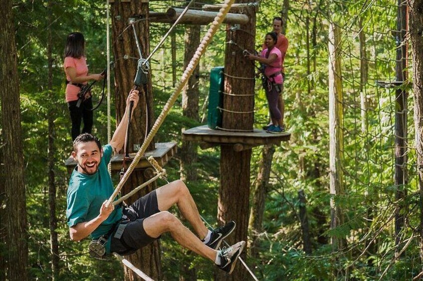 An individual on a rope course in a forested area. 1