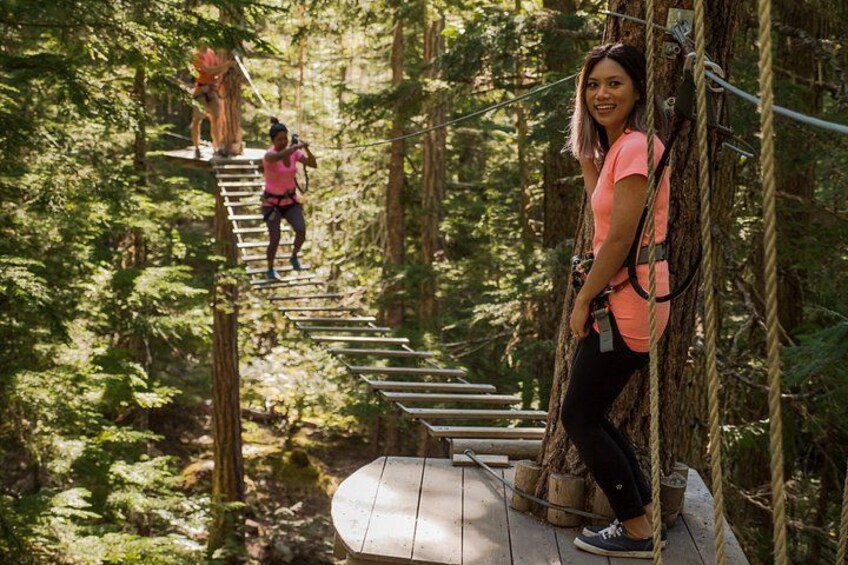 A person on a rope bridge in a forest. 4