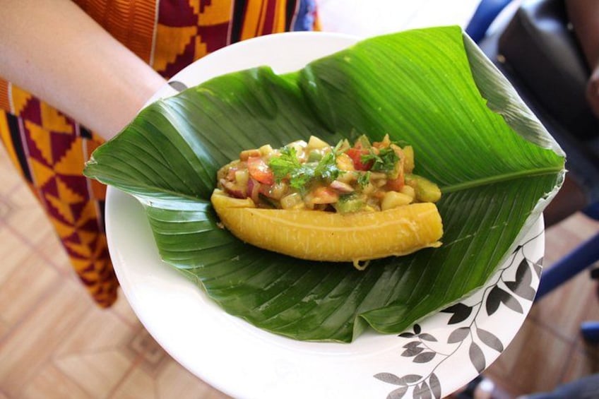 A banana wrapped in a green leaf, held by a person wearing a patterned garment. 3
