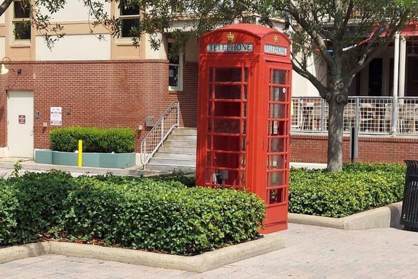 En röd brittisk telefonkiosk i ett välordnat område, med en byggnad i tegel som syns i bakgrunden. 3