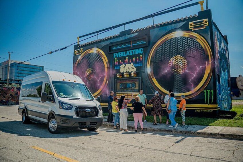 A white van parked in front of a large food truck with a honeycomb design and the words 'EVELASTING' and 'TASTY' on the side. 1