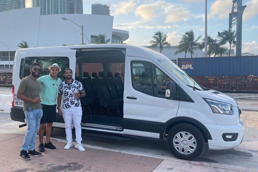 A white van parked on a street with three people standing beside it. 5
