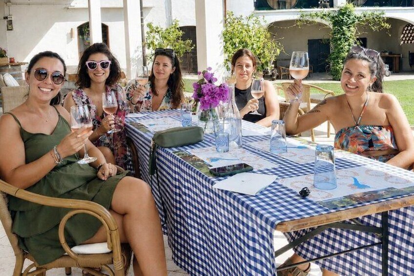A group of people sitting at an outdoor table with a checkered tablecloth, holding wine glasses. 5