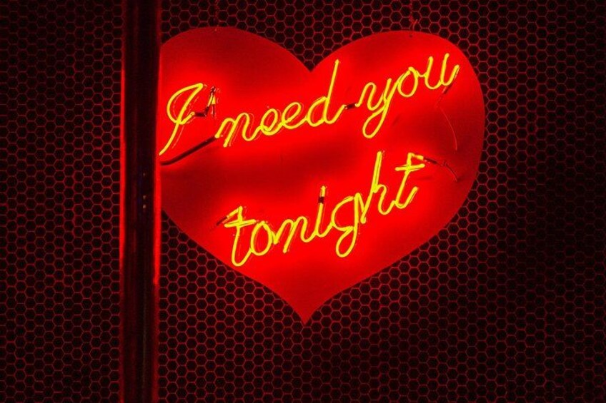 Un corazón de neón rojo con el texto 'I need you tonight' sobre un fondo de panal. 4