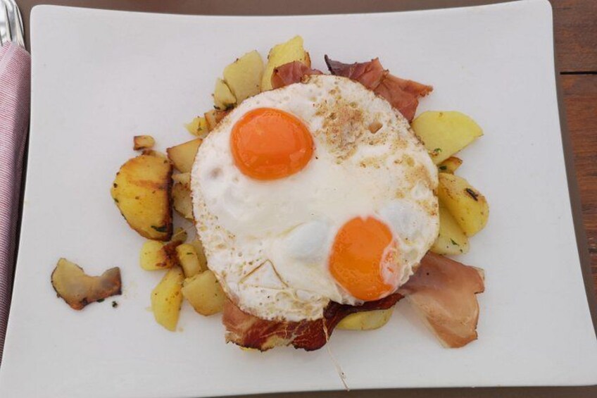 A plate with a fried egg, potatoes, and bacon. 4