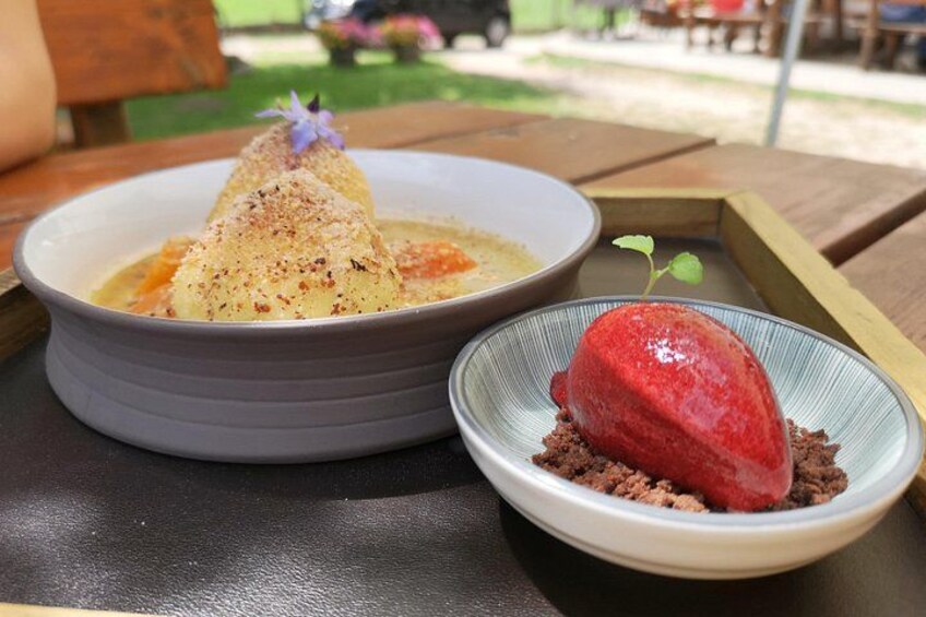 Two dishes on a table, one with a mound of food and the other with a red dessert on a bed of crumbled chocolate. 3