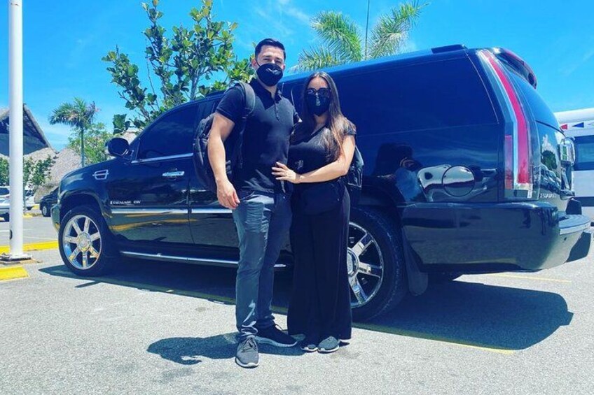 A black SUV parked in a parking lot with a clear blue sky and palm trees in the background. 2