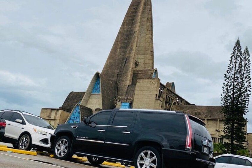 A black SUV parked in front of a large, pyramid-shaped building with blue windows. 4