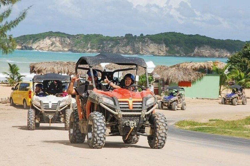 Off-road vehicles on a beach with a clear view of the ocean and hills in the background. 1