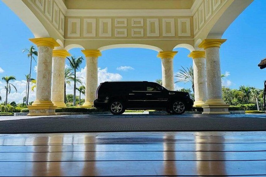 A black SUV parked under a white and yellow pavilion with palm trees in the background. 5
