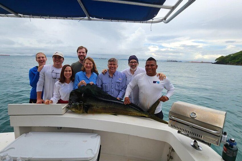 A group of people on a boat with a large fish on the deck. 2