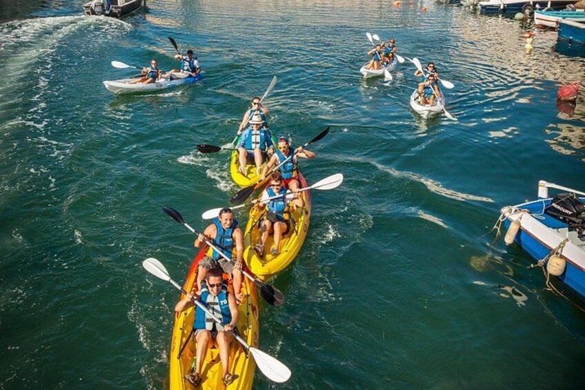 People kayaking on a calm body of water with boats docked nearby. 2