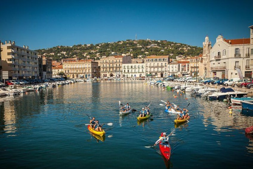 A marina with several kayaks and canoes, buildings, and a hilly landscape in the background. 4