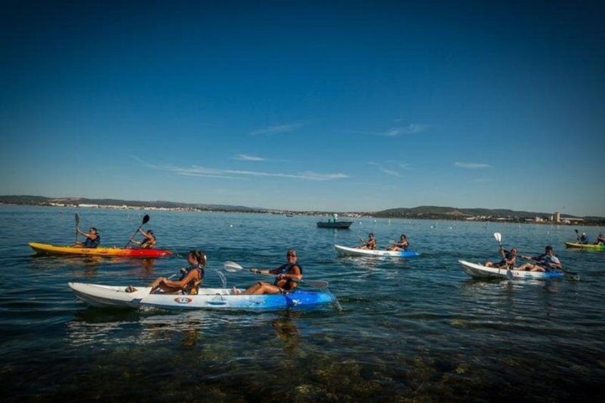 People kayaking on a calm body of water with a clear sky. 3