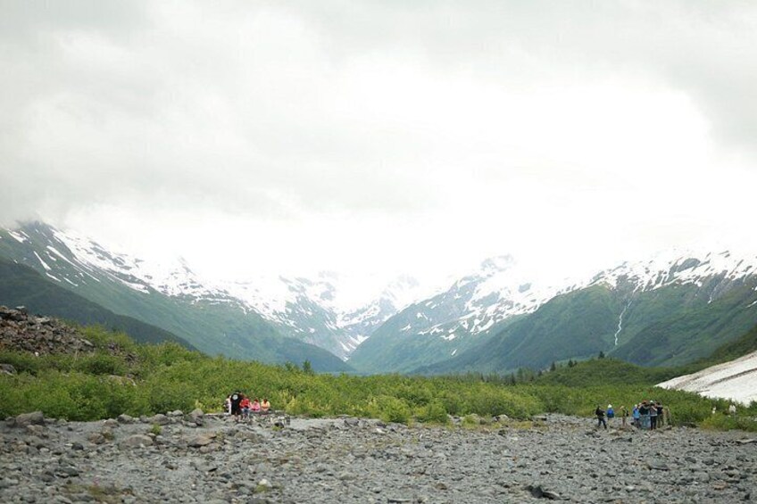 Un paisaje rocoso con montañas al fondo y un grupo de personas al frente. 4