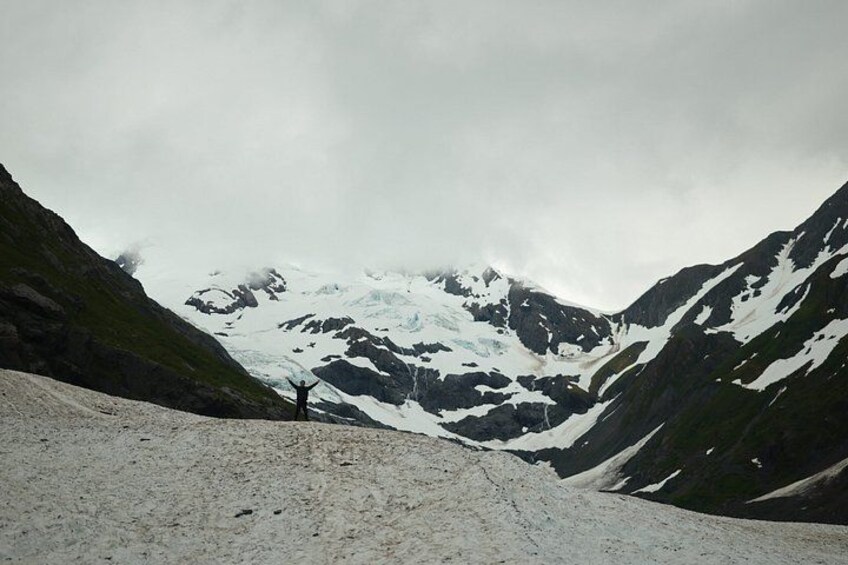 Ein schneebedeckter Berg mit einer Person auf einem Schneeplateau. 3