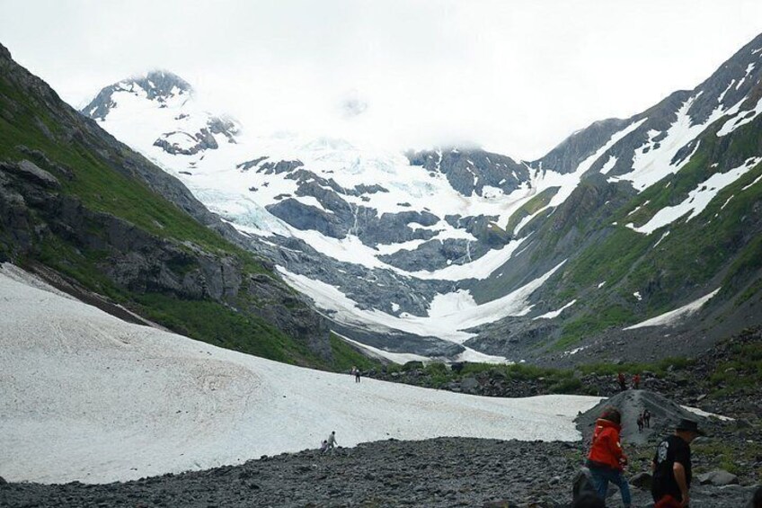 Valle glaciar con terreno rocoso y parches de nieve, rodeado de montañas. 5
