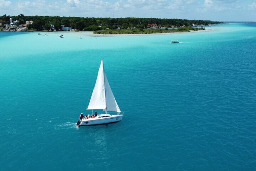 A sailboat on turquoise waters with a coastline in the background. 5