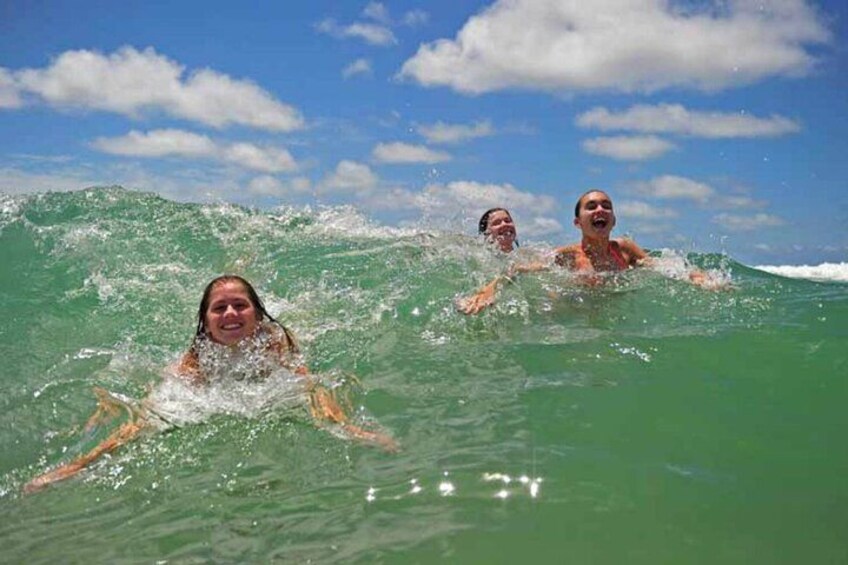 Three people swimming in the ocean with waves. 3
