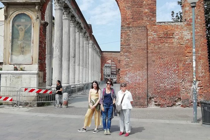 Un groupe de personnes se tient devant un bâtiment historique, orné de colonnes et d’une grande peinture. 3