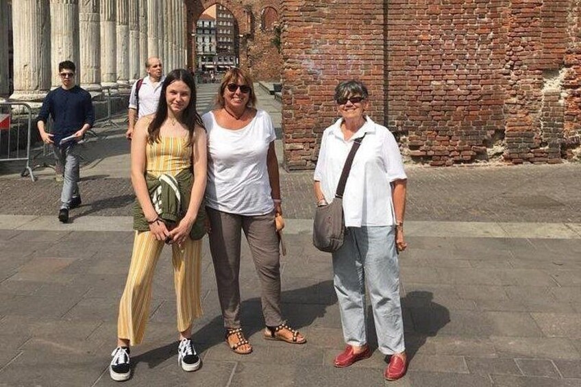 Un groupe de personnes se tient devant d’anciennes colonnes et un mur de briques. 4