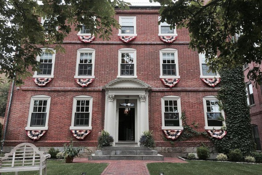 A red brick building with white trim, a central entrance, and decorative wreaths on the windows. 3