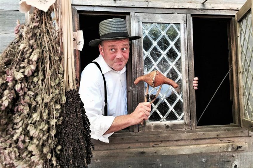 A person holding a wooden tool near a window with a lattice design. 5