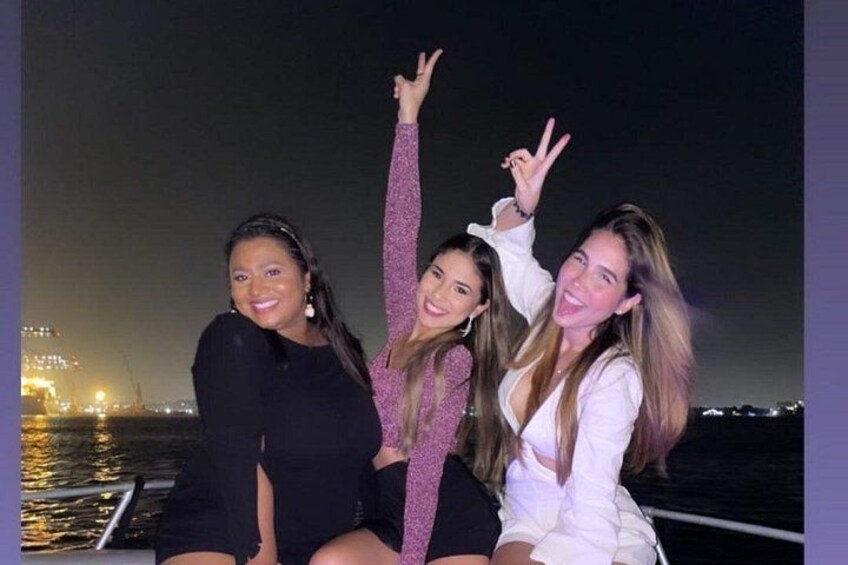Three people on a boat at night with city lights in the background. 5
