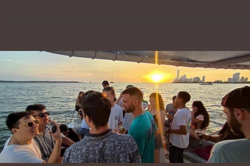 A group of people on a boat during sunset with a city skyline in the background. 4