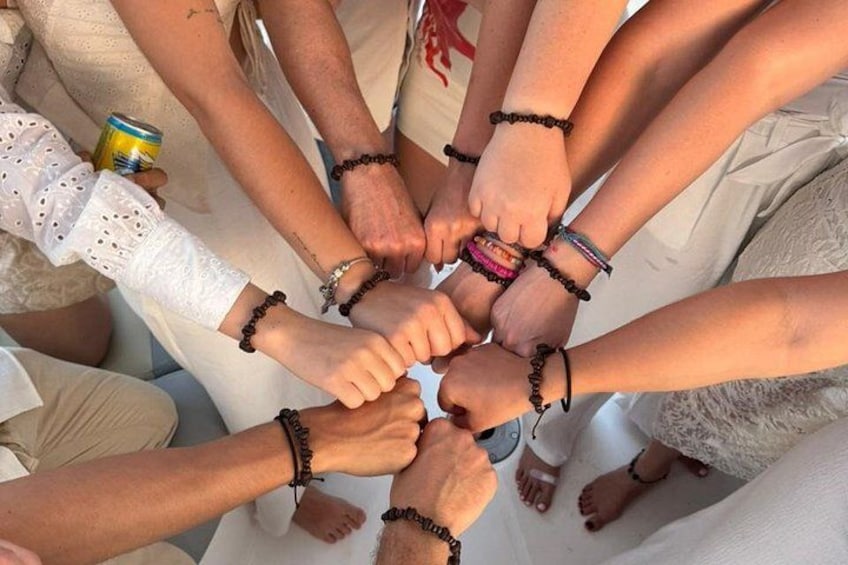A group of people with their hands joined together in a circle, wearing bracelets. 2