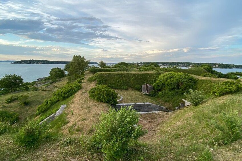 Un paysage verdoyant avec un petit bâtiment, un sentier et une étendue d’eau en arrière-plan. 2