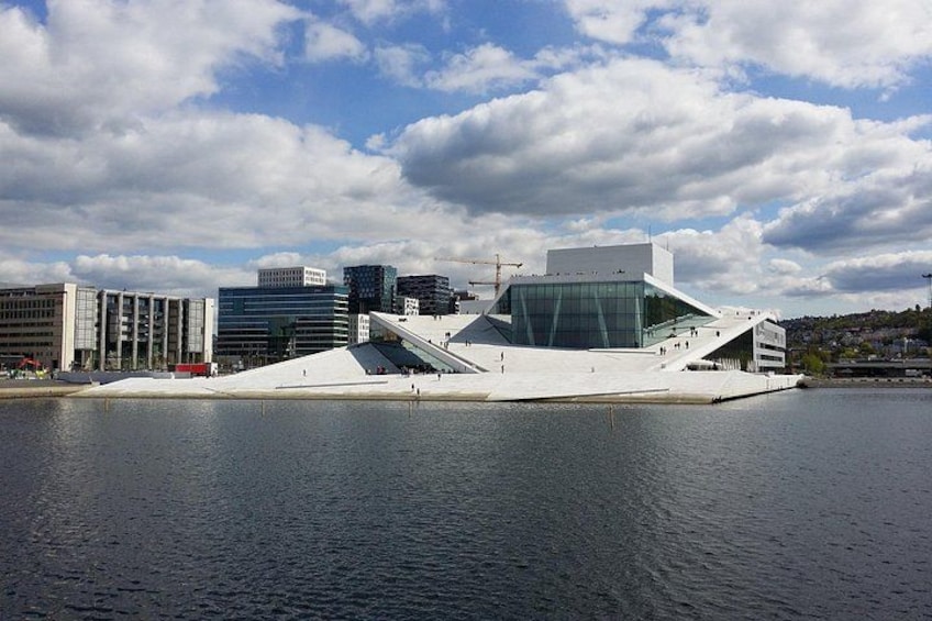 Ein modernes Gebäude mit markanter, dreieckiger Architektur, gelegen an einem Gewässer, mit weiteren Gebäuden im Hintergrund. 2