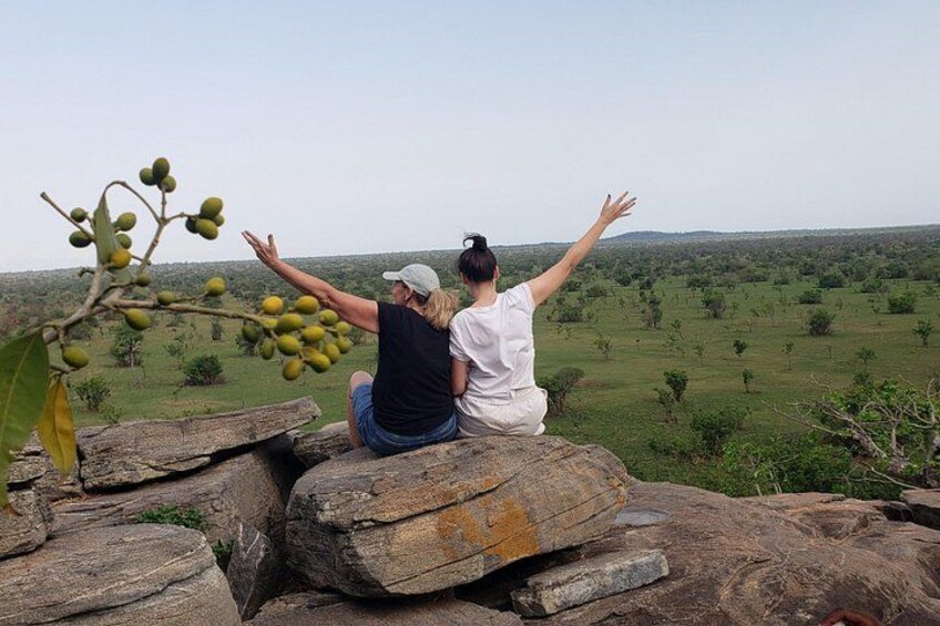 Dos personas sentadas sobre rocas con vistas a un paisaje verde. 2