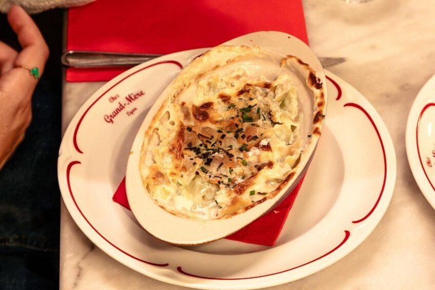 A dish of baked potatoes garnished with herbs, served on a white plate with red accents. 4