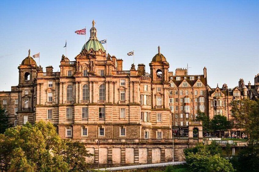 Un edificio histórico con varias banderas, una cúpula destacada y arquitectura clásica. 3