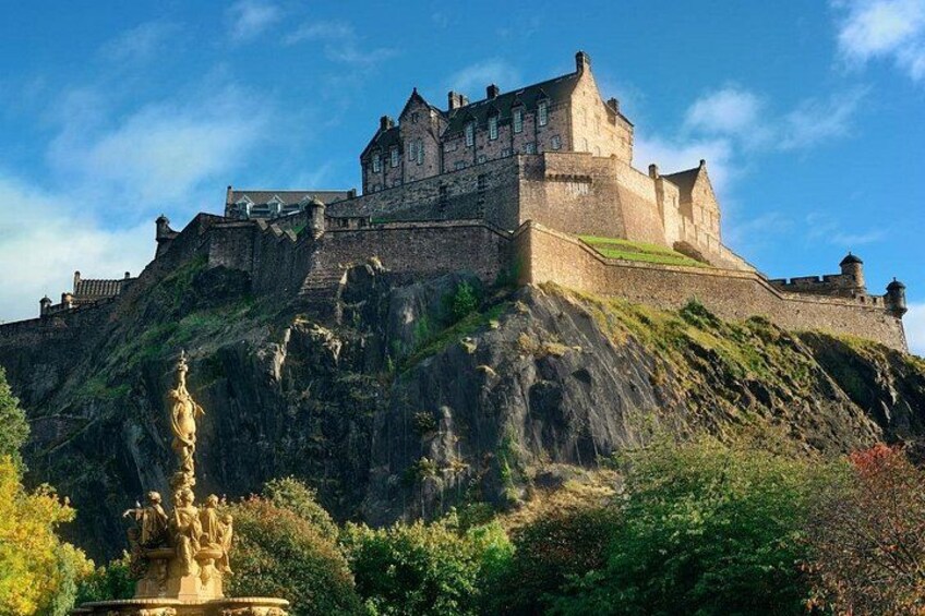 A castle on a hill with a statue in the foreground. 1