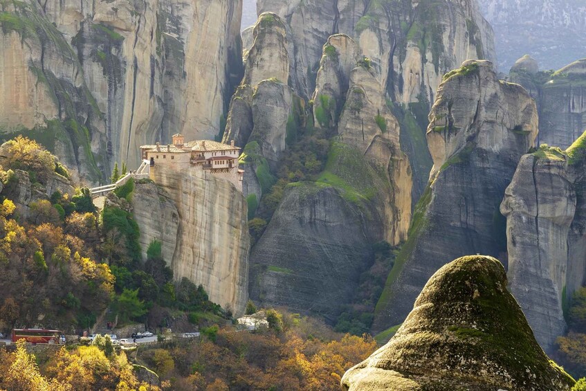 A monastery perched on a cliff with a lush forest below. 4