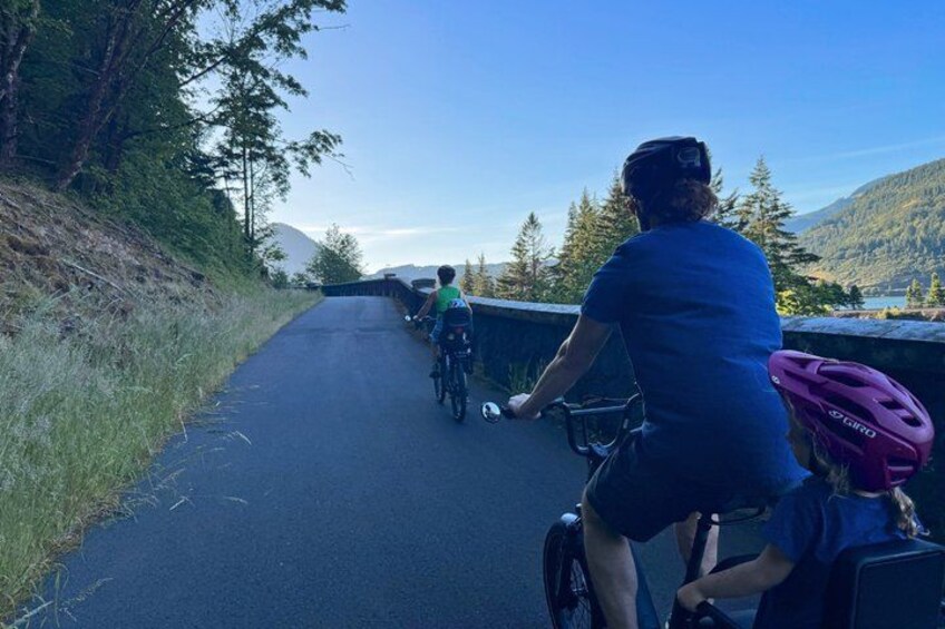 A paved road with cyclists, surrounded by trees and hills. 3
