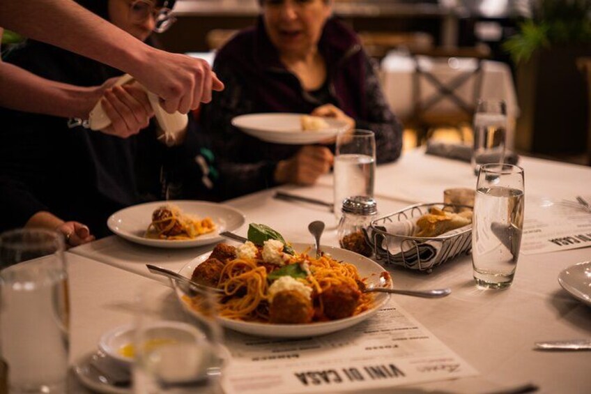 A dining table with plates of food, glasses of water, and a menu. 3