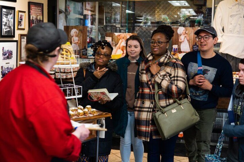 A group of people in a store with a display of pastries. 1