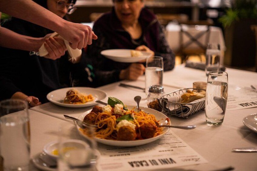 A dining table with plates of food, glasses of water, and a menu. 3