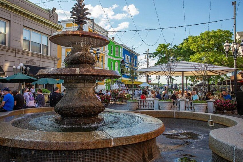 A multi-tiered fountain in a public square with people sitting and walking around. 2